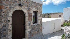 A stone building with a brown door, a window, and a sign that reads "nomas." - Nomas  Skaloti House (Skaloti)