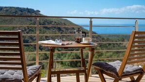 A wooden table with a coffee pot, cup, and glasses on a balcony overlooking a mountainous landscape. - Nomas  Skaloti House (Skaloti)