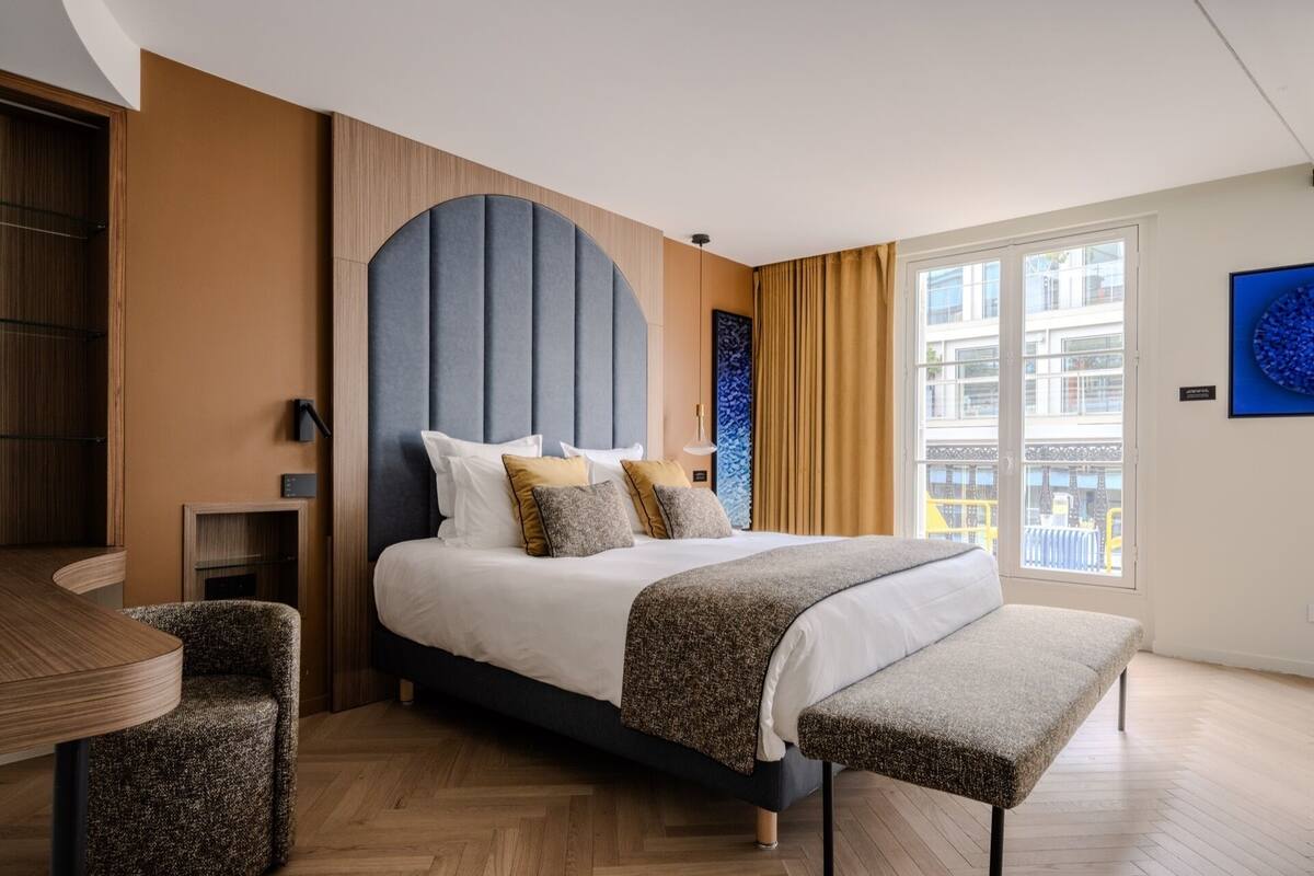 Una habitación de hotel moderna con una cama grande, un escritorio y un banco.