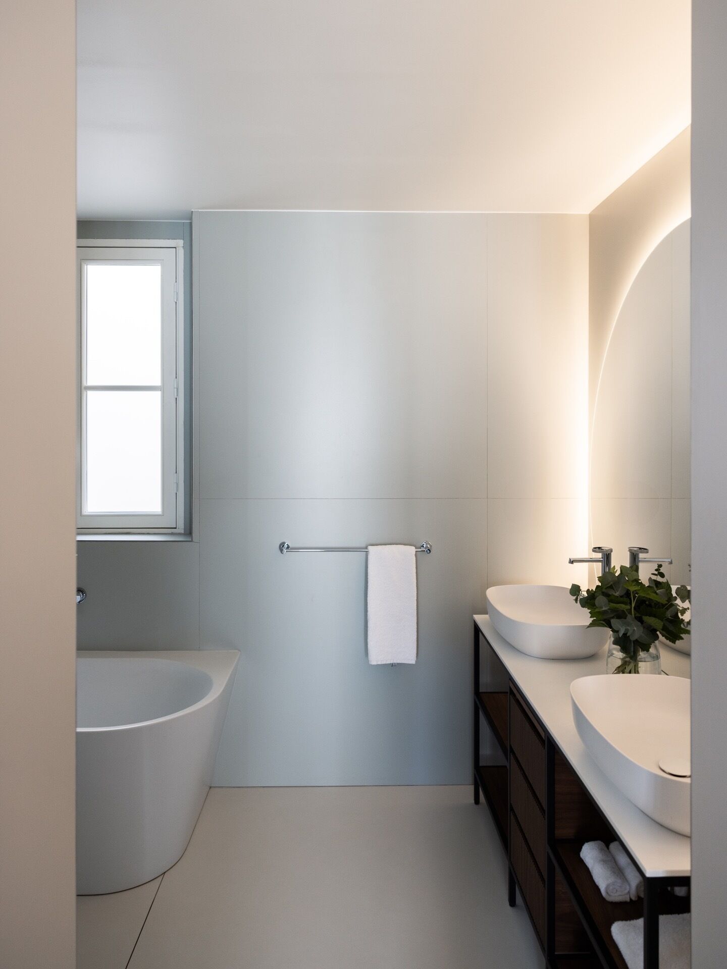 Ein modernes Badezimmer mit freistehender Badewanne, einem Waschtisch mit runder Spüle und einem Handtuchhalter.