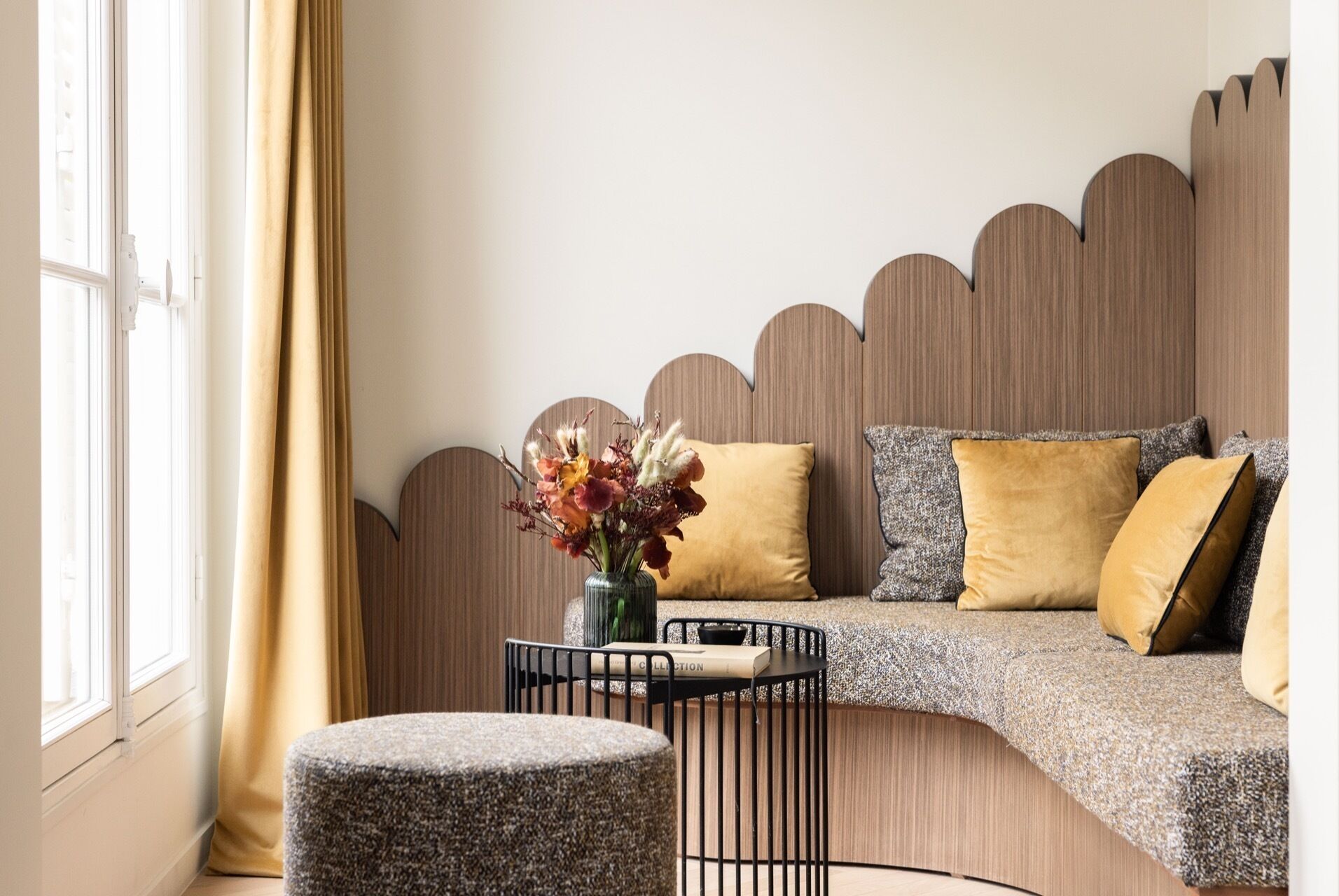 A modern living room with a curved sofa, a small round table, and a decorative wall panel.