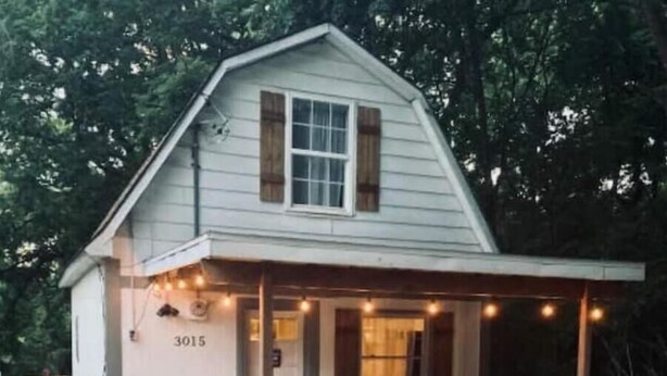 A small, single-story house with a porch, numbered 3015, surrounded by trees.