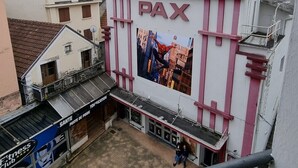 Un cine con un gran letrero que dice "Cinema PAX" y un cartel de un superhéroe.