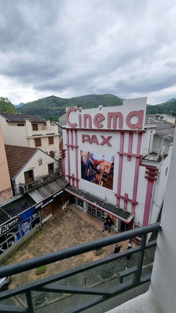 Un cine con un gran letrero que dice "Cinema PAX" y un cartel de un superhéroe.
