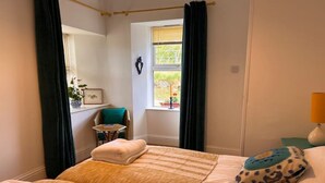 A bedroom with a bed, a chair, a window, and a lamp. - Berry View - Idyllic cosy cottage on berry farm (Rattray)