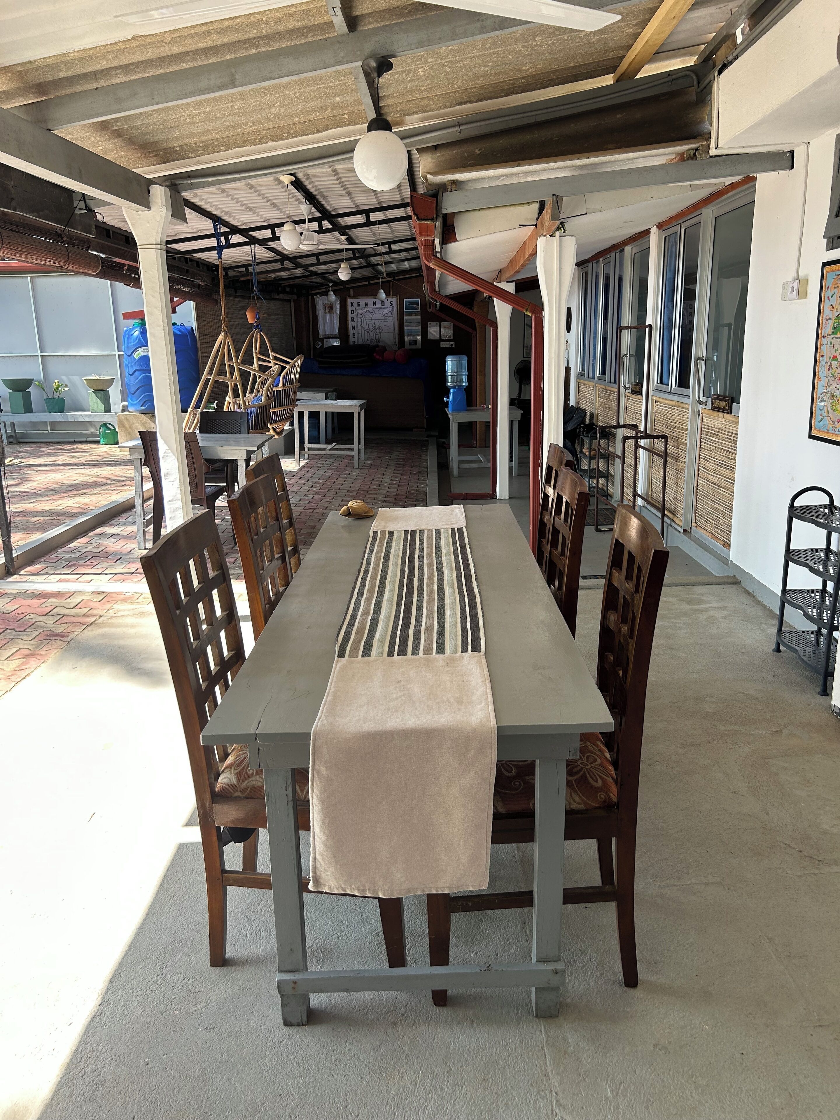 A dining area with a long table, chairs, a hanging light fixture, and a water dispenser.