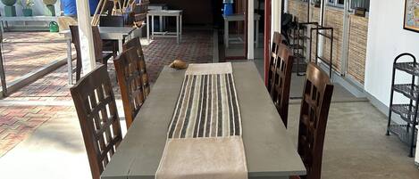 A dining area with a long table, chairs, a hanging light fixture, and a water dispenser.