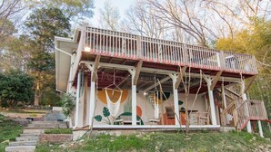 A wooden deck with a railing, a staircase leading up, and a hanging chair.