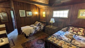 Une pièce rustique en bois, avec deux lits, un banc et un tapis.