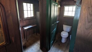 Une salle de bain en bois avec des toilettes, une petite fenêtre et un banc en bois.