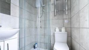 A modern bathroom with a glass shower enclosure, a white toilet, and a sink with a cabinet.