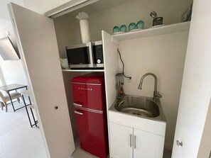 Cozinha compacta com uma geladeira vermelha Galanz, micro-ondas e pia.
