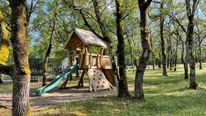 A wooden play structure with a slide and climbing wall in a park. - Chalet Nature - Lodges du Bois Dodo (Septfonds)