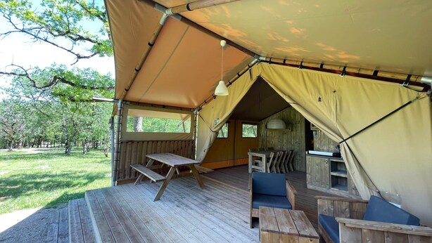 Una carpa con una terraza de madera, una mesa y asientos.