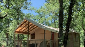 Eine rustikale Holzhütte mit einer Holzterrasse, einer Veranda und einem eingezäunten Bereich.