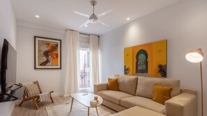 A modern living room with a sofa, a coffee table, a TV, a ceiling fan, and artwork on the walls. - Charming 2-Bed Apartment in Conde Duque, Madrid (Madrid)