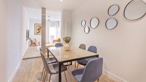 A modern dining area with a glass-top table, six chairs, and a vase of flowers. - Charming 2-Bed Apartment in Conde Duque, Madrid (Madrid)