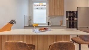 A modern kitchen with a central island, wooden cabinets, a built-in oven, and a refrigerator. - Charming 2-Bed Apartment in Conde Duque, Madrid (Madrid)