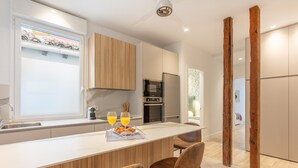 A modern kitchen with a central island, wooden cabinets, and a built-in oven. - Charming 2-Bed Apartment in Conde Duque, Madrid (Madrid)