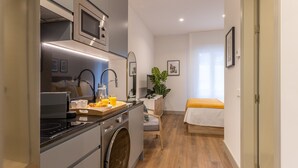 Une cuisine compacte dotée d’appareils électroménagers modernes, d’un lave-linge et d’un coin repas avec un lit.