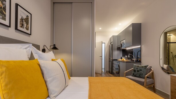 Une chambre d’hôtel moderne équipée d’un lit, d’un bureau et d’une kitchenette.