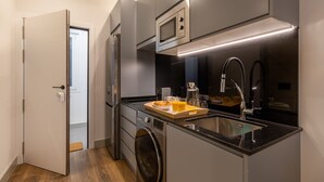 Une cuisine compacte équipée d’un four à micro-ondes encastré, d’un évier et d’une machine à café.