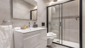 A modern bathroom with a glass-enclosed shower, a white vanity with a mirror, and a toilet.