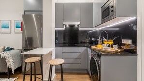 A compact kitchen with modern appliances, a small dining area, and a washing machine.
