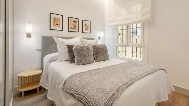 A bedroom with a bed, a bedside table, and a window with a view.