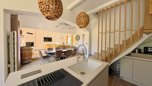Una cocina moderna con una isla integrada, un área de comedor con sofá amarillo y una escalera de madera.