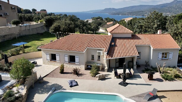 Una villa con piscina, mobiliario de exterior y vistas al mar.