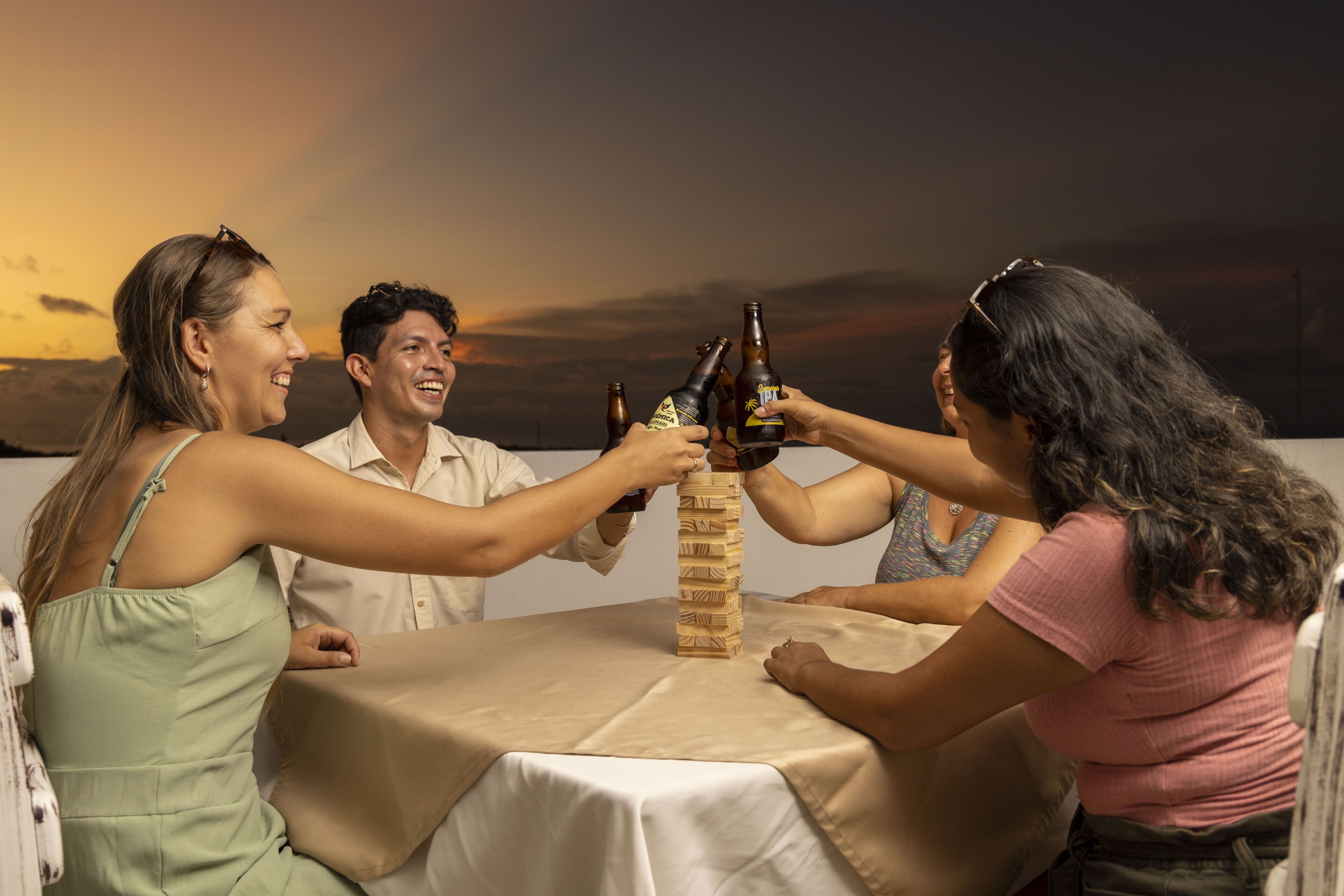 A group of people toasting with beer bottles around a wooden tower.