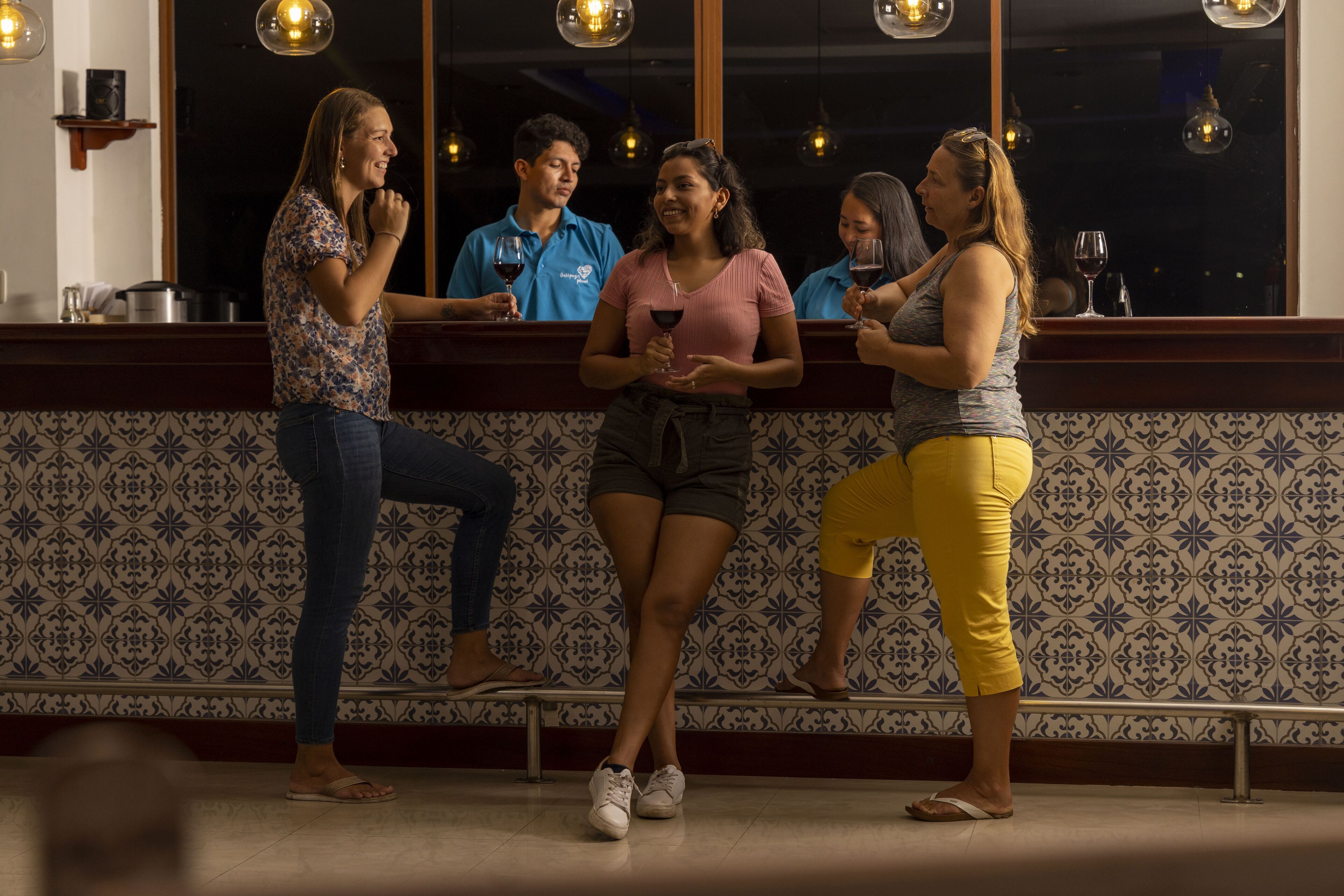 Zona de bar con pared decorada y luces colgantes.