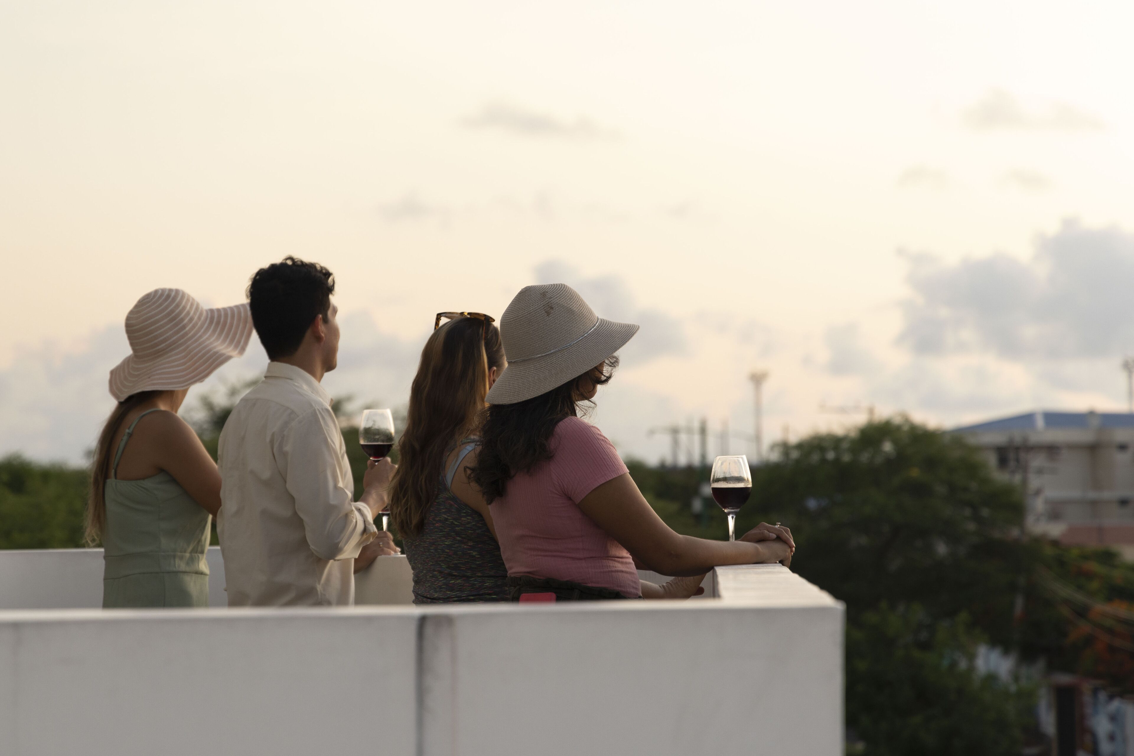 Cuatro personas sentadas en una terraza en la azotea, con vistas al horizonte de la ciudad.