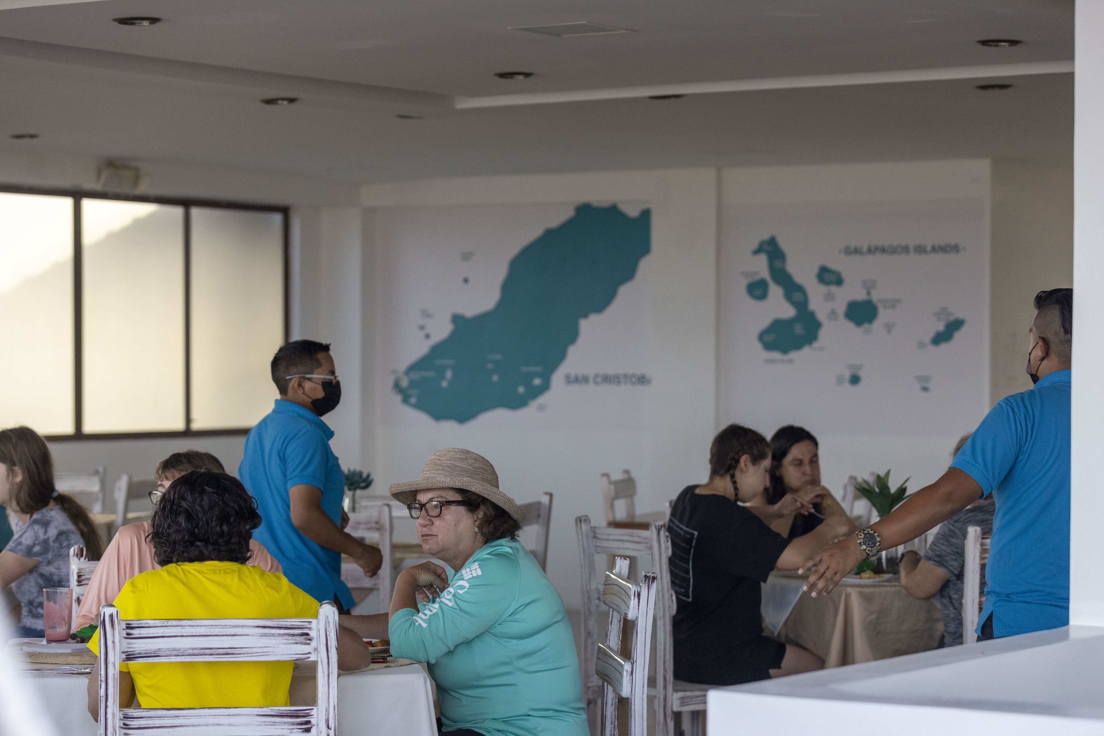A restaurant with tables and chairs, a map on the wall, and people dining.