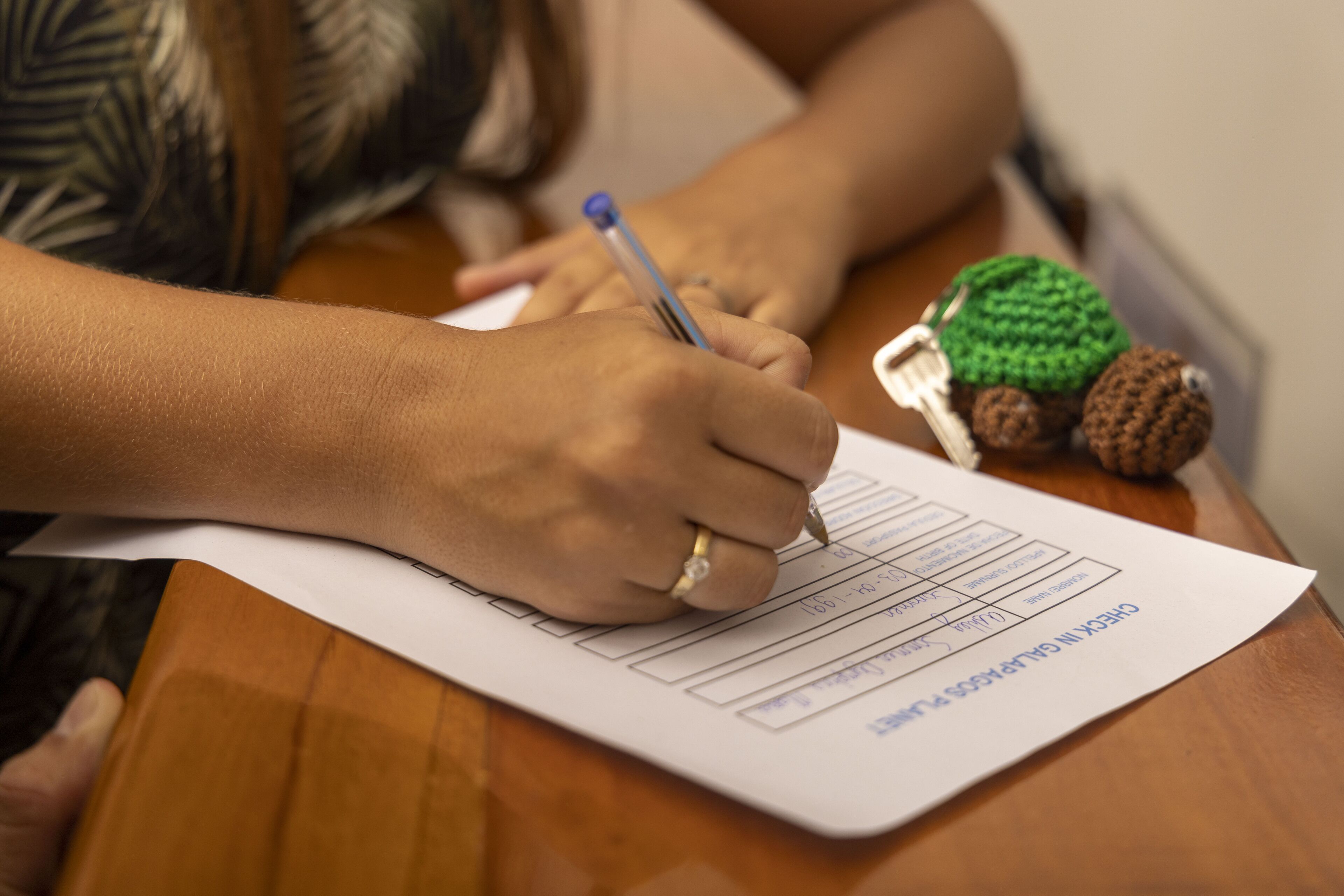 A person filling out a form on a wooden table.