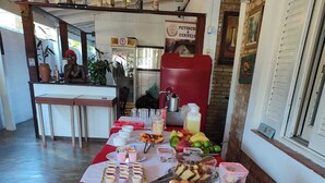 A buffet table with various food items and utensils. - Pousada Renoah (Ubatuba)