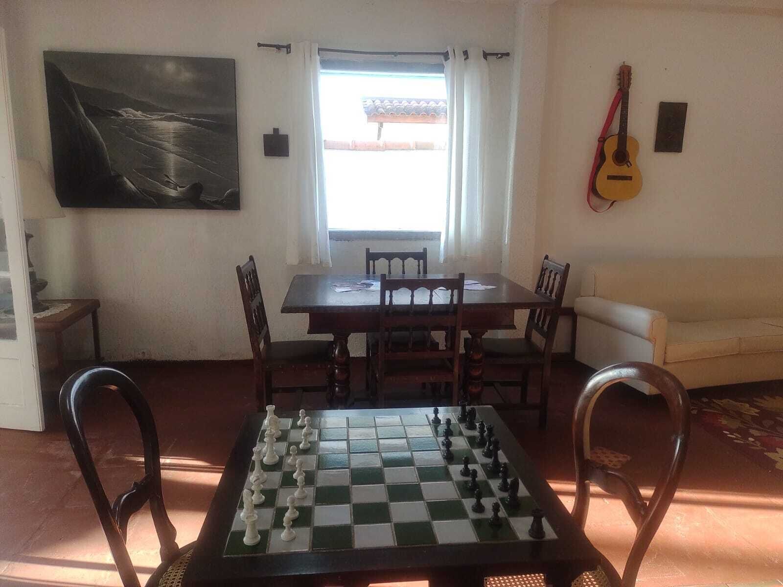 Uma área de refeições com um tabuleiro de xadrez, uma pintura e uma guitarra na parede.