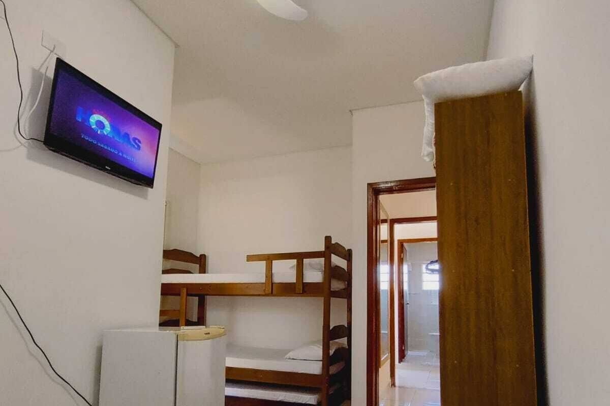 A bedroom with bunk beds, a television on the wall, and a ceiling fan.