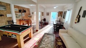 A living room with a pool table, a sofa, and a coffee table. - Pousada Renoah (Ubatuba)
