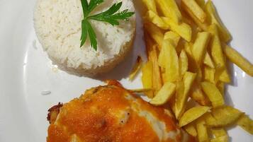 Un plato con arroz blanco, papas fritas y un trozo de pollo frito.