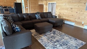 L’intérieur d’une cabane en rondins moderne, avec un canapé modulable, des poufs et un tapis à motifs.