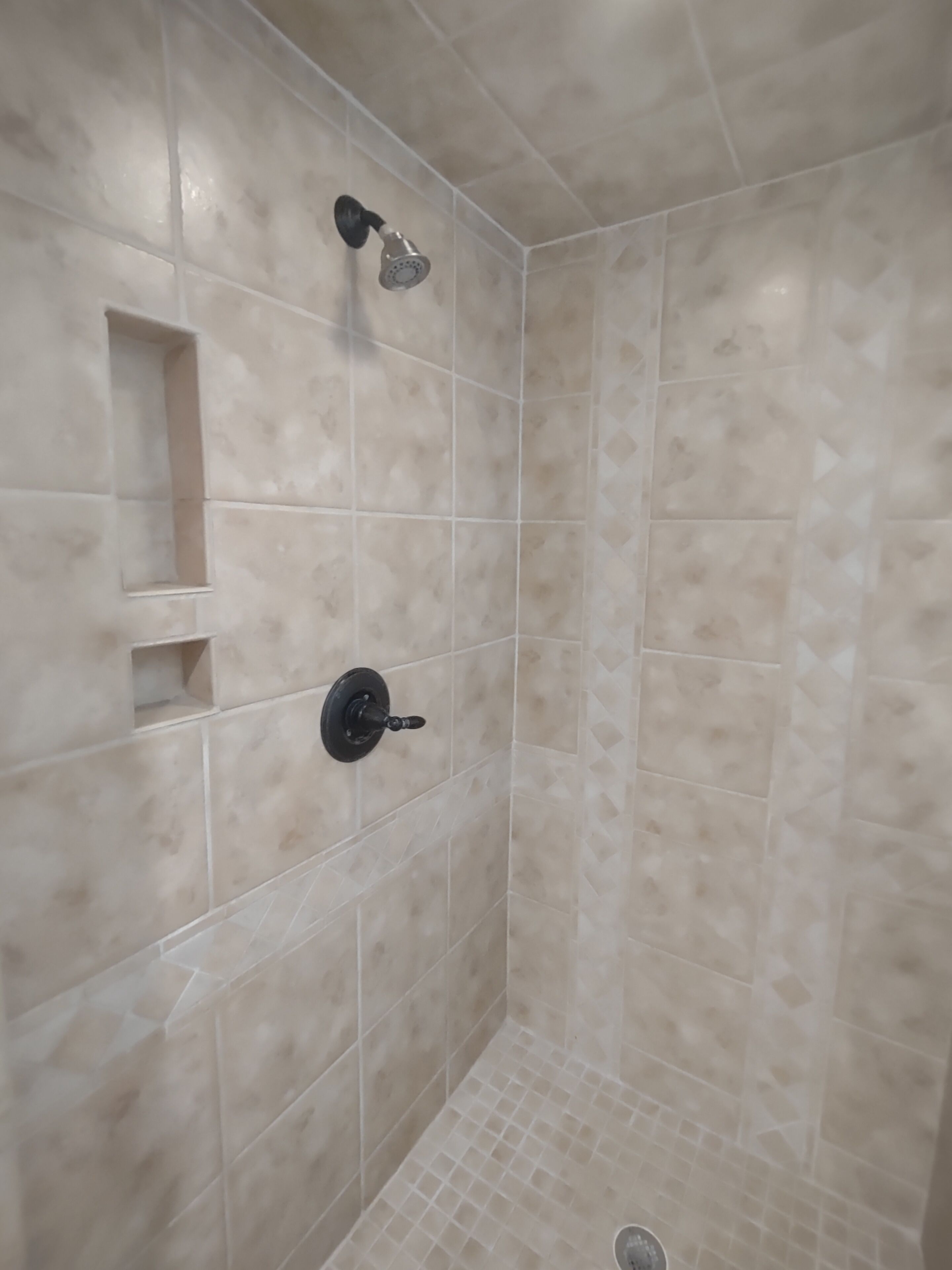 A shower with a handheld showerhead and a wall-mounted faucet.