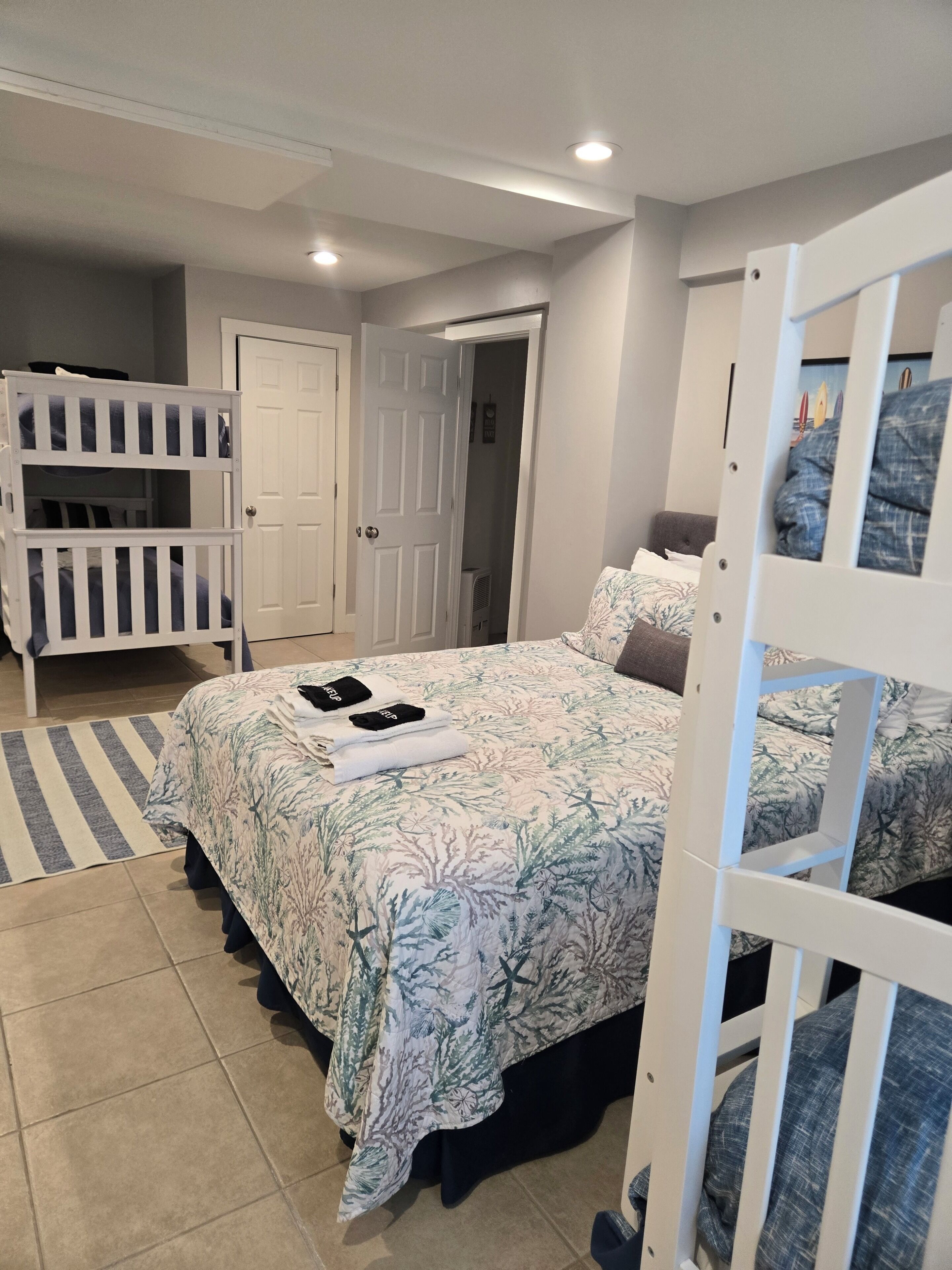 A bedroom with bunk beds, a bed with a floral bedspread, and a striped rug.