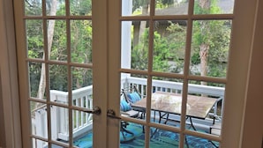 Una puerta corrediza de vidrio da a un patio exterior con piscina, mobiliario de terraza y follaje circundante.