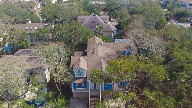 Zona residencial con casas rodeadas de vegetación densa y una playa al fondo.