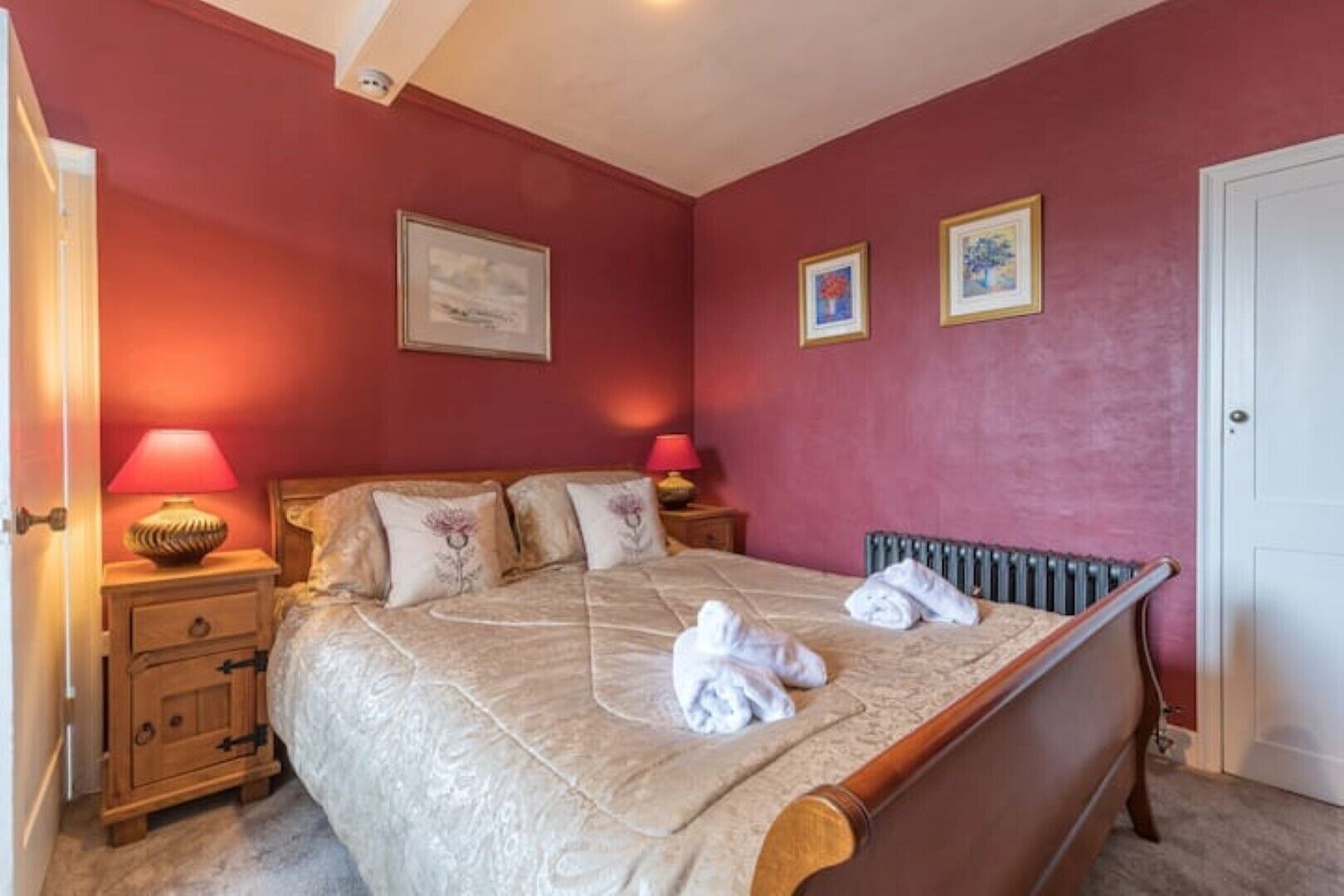 Une chambre à coucher avec un lit, deux tables de chevet, un radiateur et une porte.
