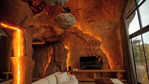 Un intérieur moderne avec un canapé, une table basse et un téléviseur, le tout placé devant un mur qui rappelle l’intérieur d’une grotte.