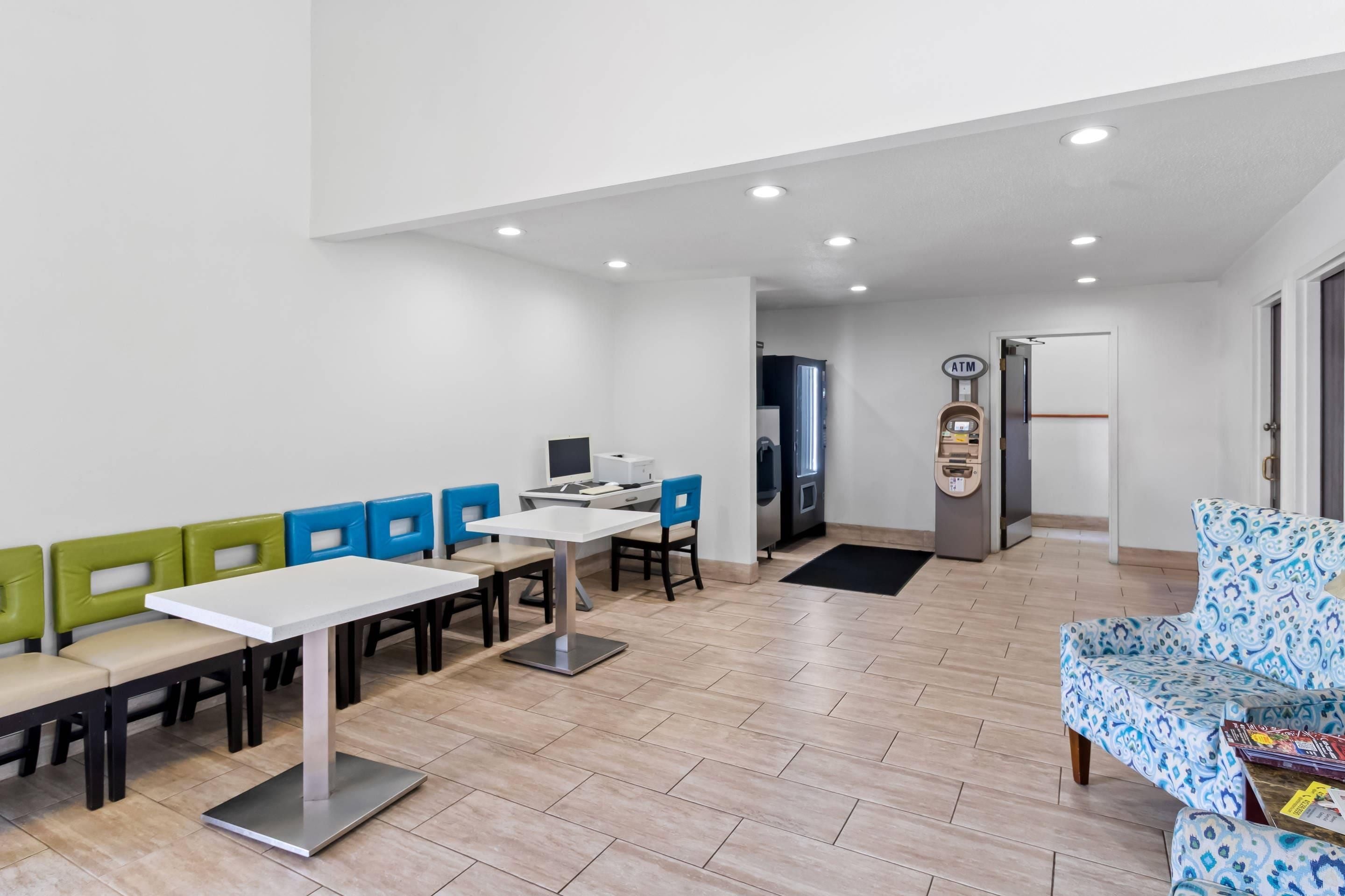Una habitación amplia con comedor, un mostrador con cajero automático y un sofá estampado.