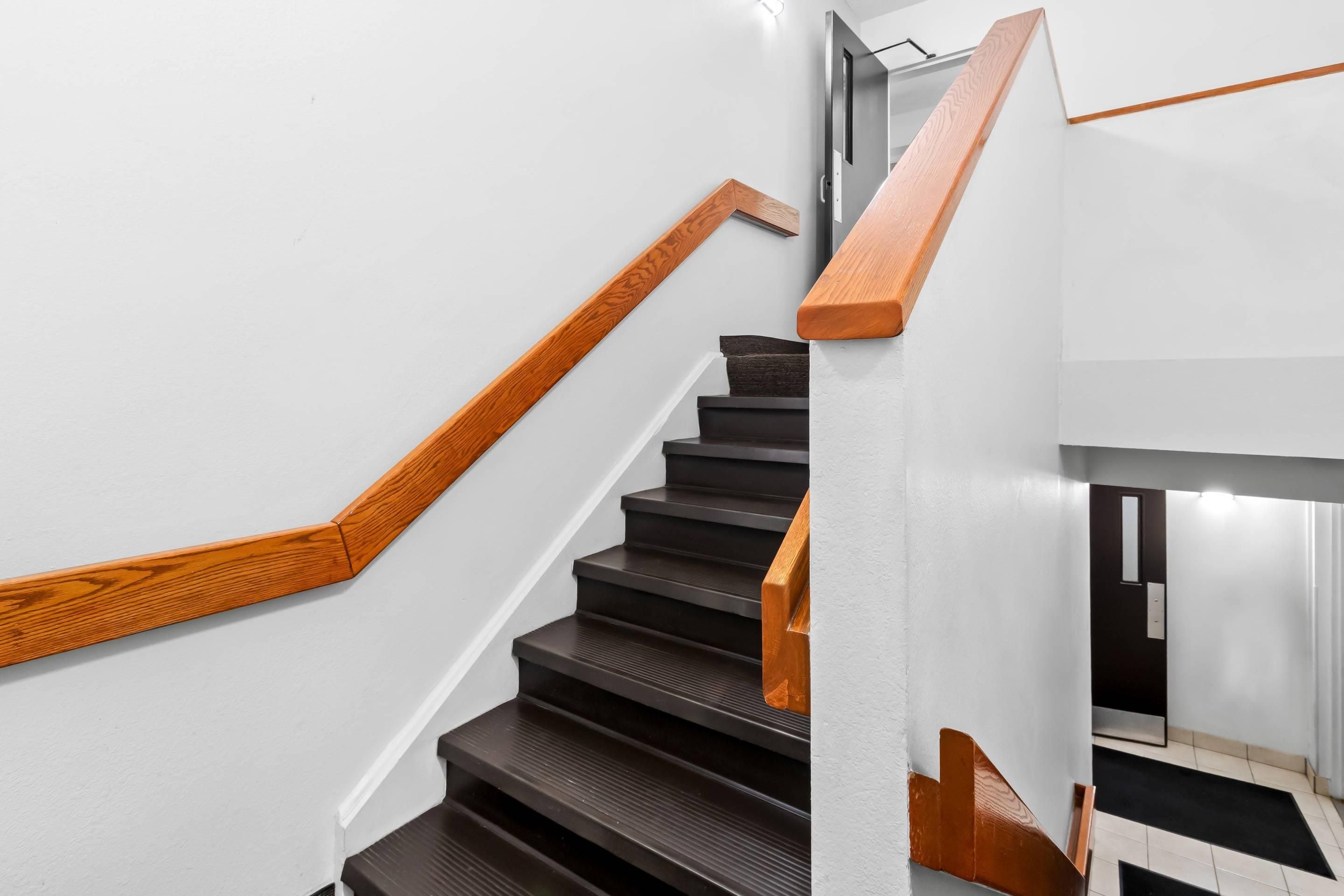 A staircase with wooden handrails and dark steps, leading to an upper floor.